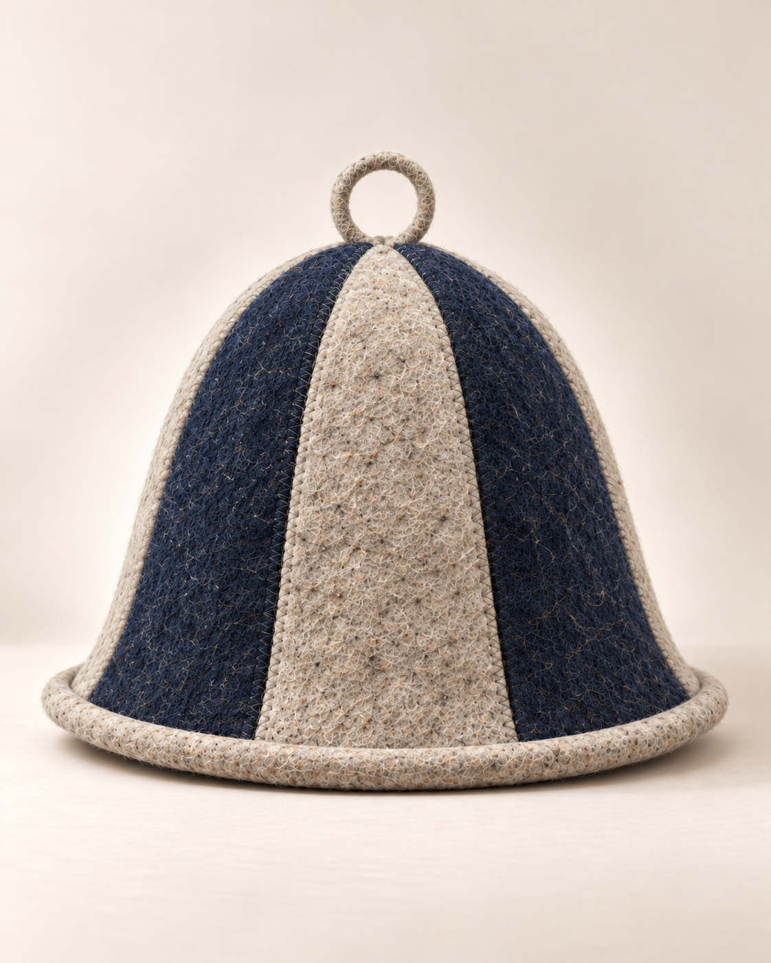 The Tonttu sauna hat: a six-panel wool felt bell shape in alternating navy and natural grey, with a small loop at the top